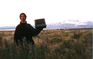 Allen. He has a lap top. He is in a field.